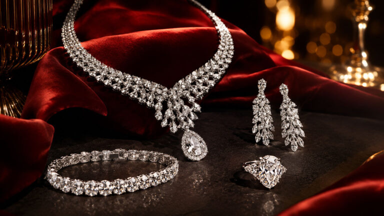 A diamond necklace, earrings, bracelet and ring arranged on red velvet.