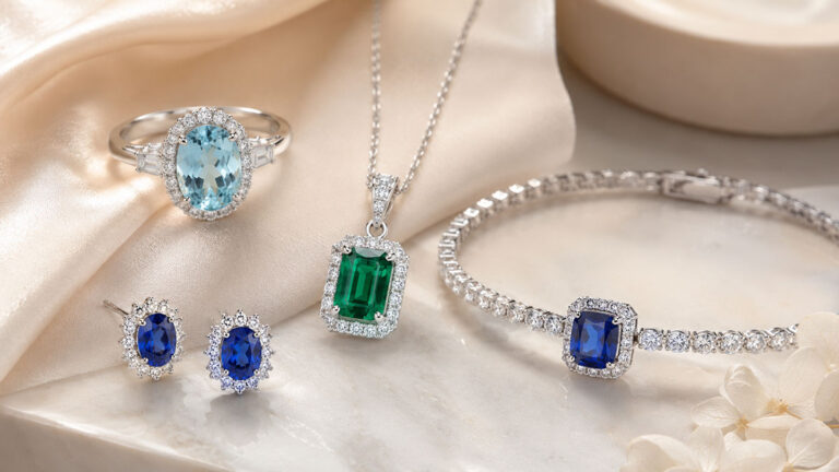 Aquamarine, emerald and sapphire jewellery set with diamonds on silk fabric.