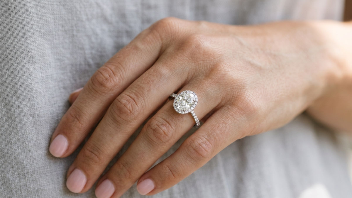 Halo diamond engagement ring on hand with larger visual look