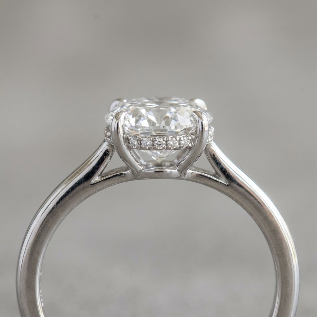 Side profile of a hidden halo engagement ring with melee diamonds beneath the center stone.