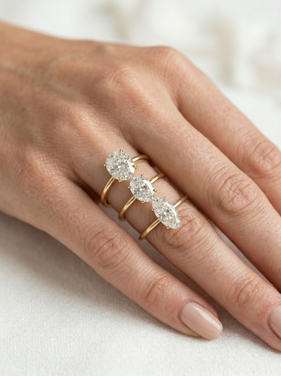 Oval diamond rings on hand showing different length-to-width ratios.